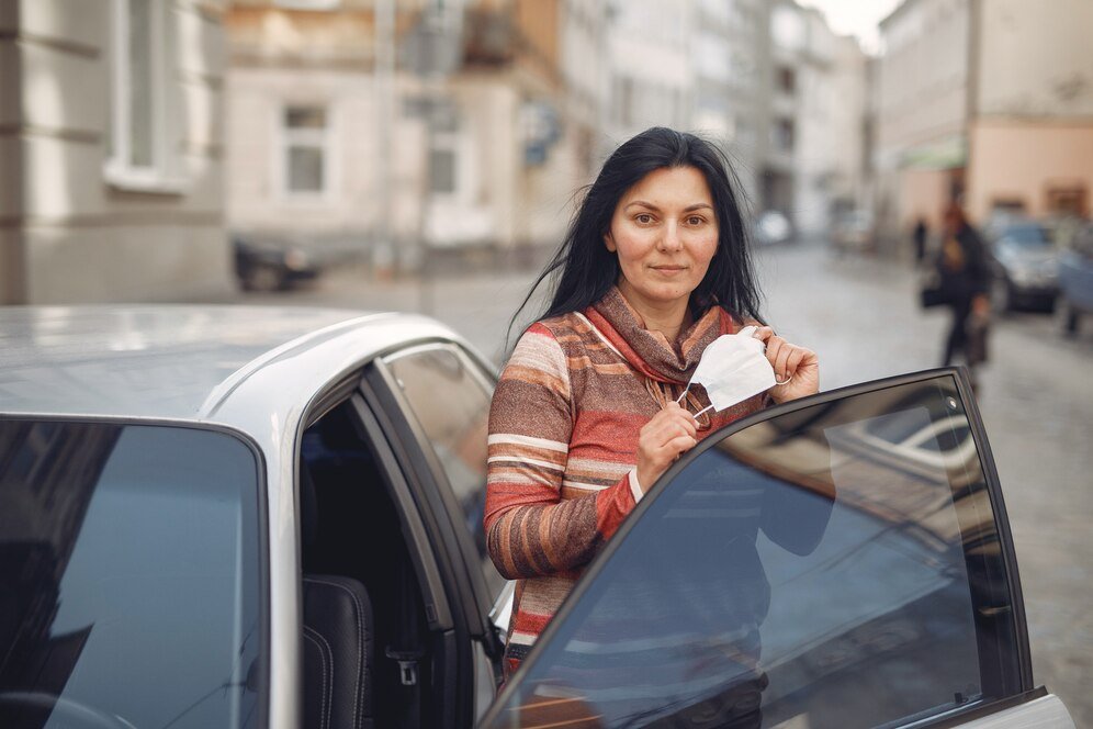 woman wearing protective mask getting into car 1157 32373